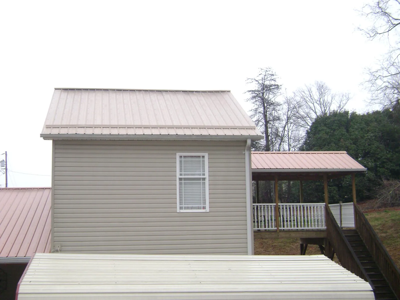 Tan metal roofs on a two story addition and attached porch, from a Roof Replacement job in Dexter